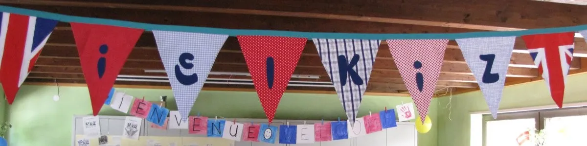 Selbstgenähte Wimpelkette mit den Buchstaben iElKiZ, darunter eine gemalte Girlande mit „Bienvenue“
